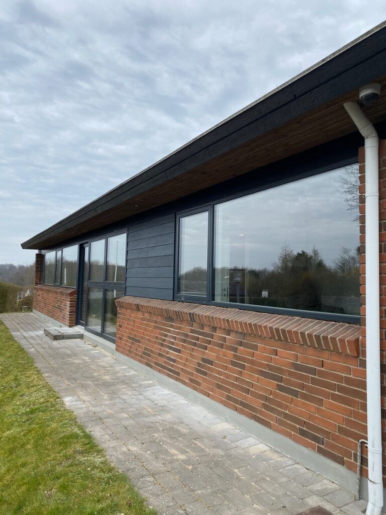 Moderne murstenshus med store vinduer og flisegang