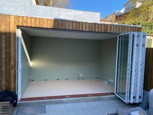 Nybygget skur med træbeklædning og store foldedøre