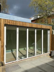 Moderne træbygning med store glasdøre i solen