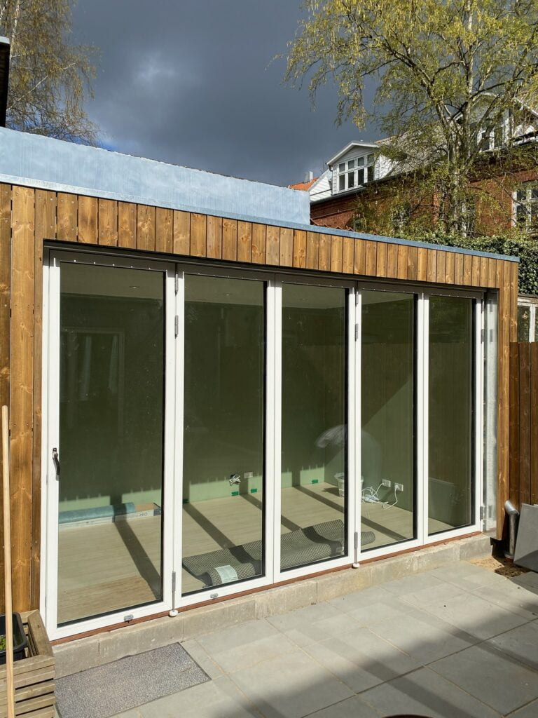 Moderne træbygning med store glasdøre i solen