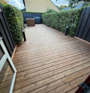 Træterrasse mellem hække med udendørs belysning