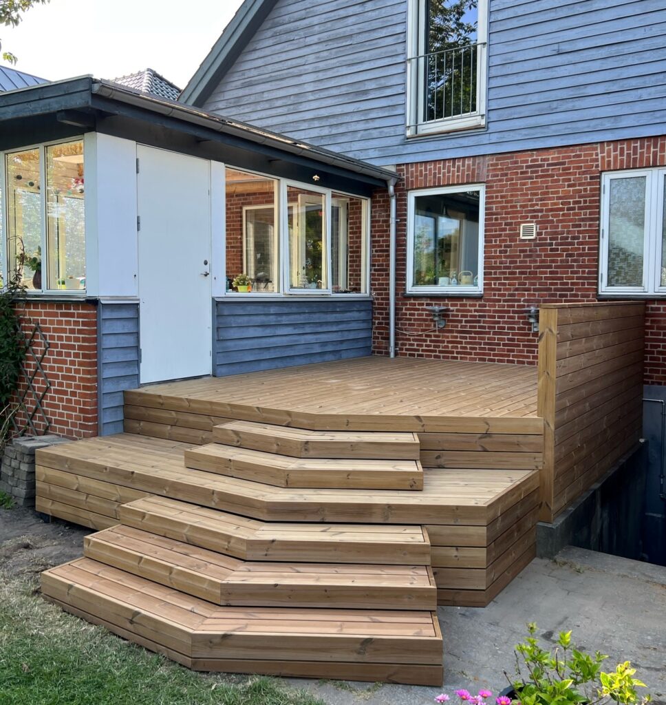 Træterrasse ved murstenshus med moderne trappe